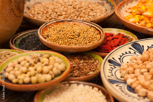 Various grain beans in small clay plates on natural textured woo