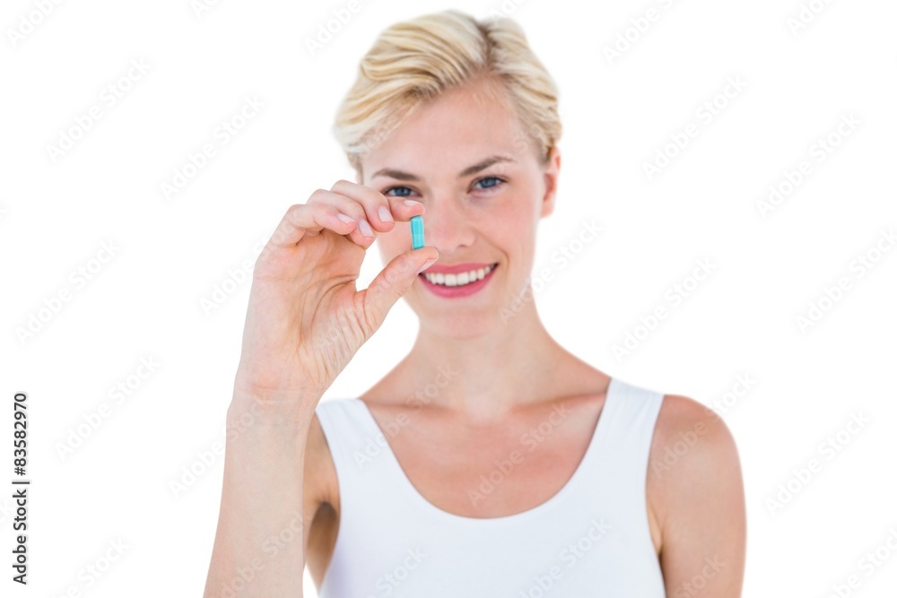 Smiling blonde woman holding blue pill Smiling blonde woman holding blue pill