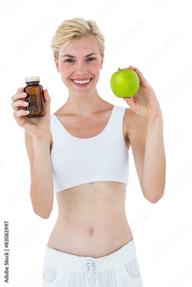 Fit blonde woman holding medicine and green apple Fit blonde woman holding medicine and green apple