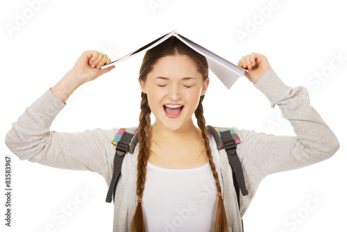 Teen girl with book over her head.