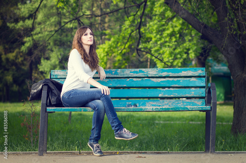 Young beautiful woman sitting on bench in park