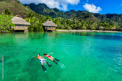 Fototapeta Naklejka Na Ścianę i Meble -  Young couple snorkeling over reef next to resort on a tropical i