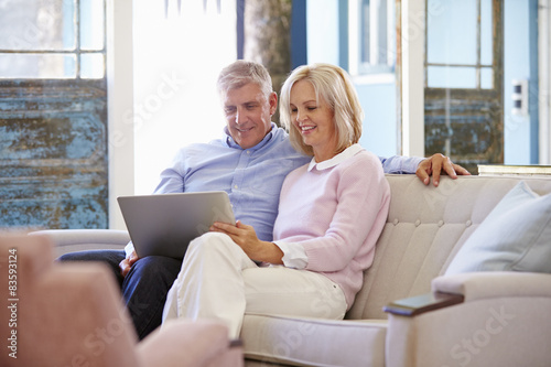 Mature Couple At Home In Lounge Using Laptop Computer