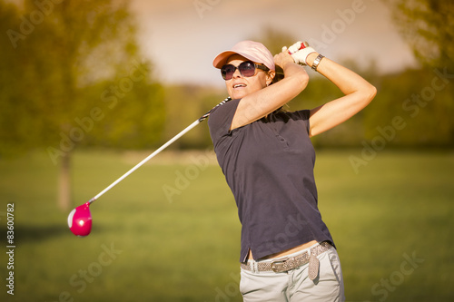 Woman golf player teeing off.