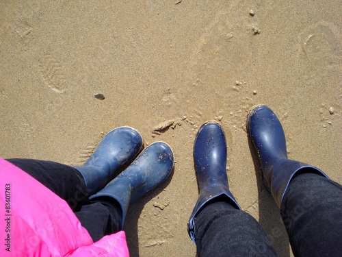 legs of a little girl and a young woman standing on a beach