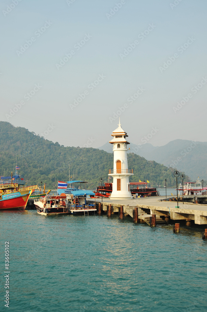 White lighthouse and pier in bay on Koh Chang island Thailand.