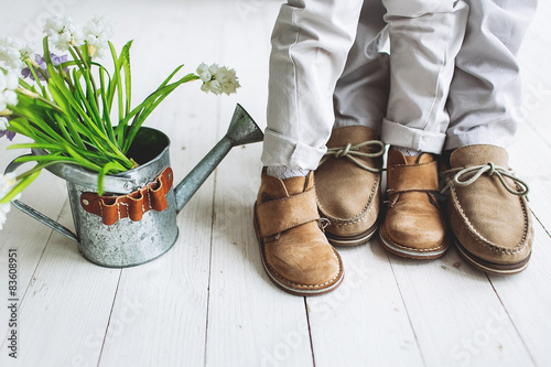 Legs of boy and man, in moccasins with flowers