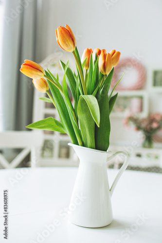 Beautiful orange flowers in vase on rustic kitchen table