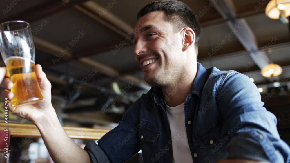 happy young man drinking beer at bar or pub