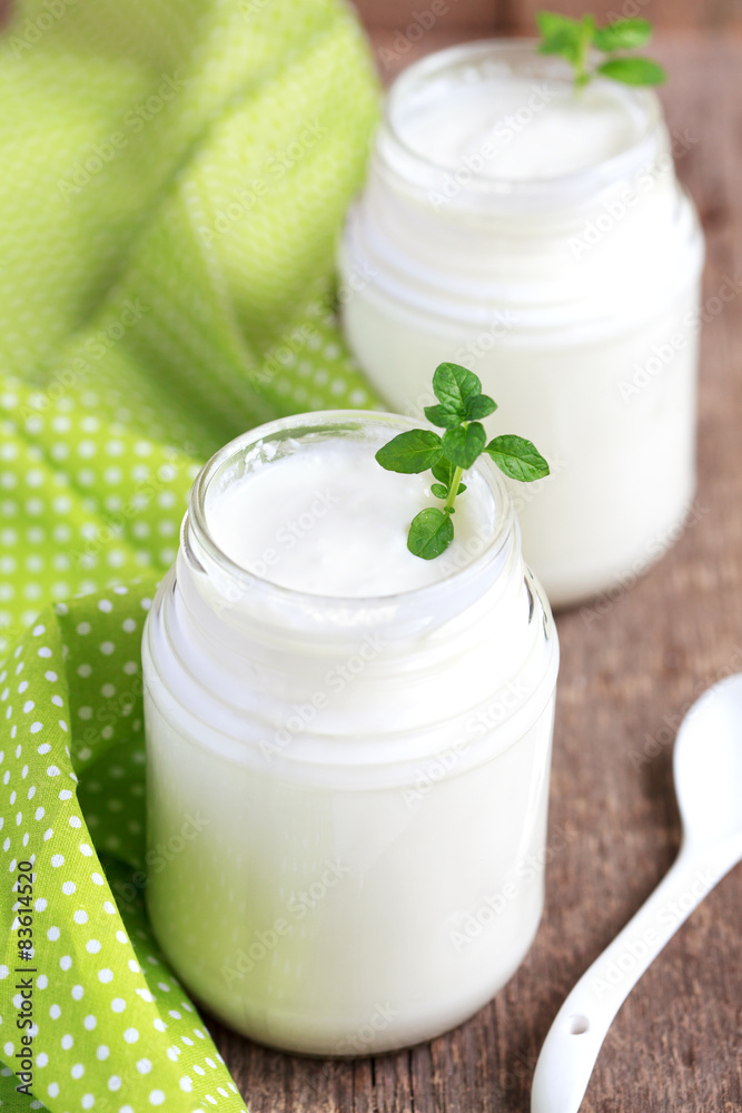Homemade yogurt in two small glass jars on a wooden table Homemade yogurt in two small glass jars on a wooden table
