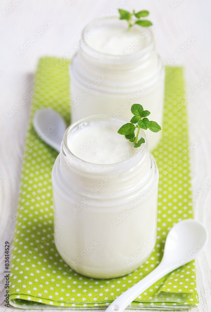 Homemade yogurt in two small glass jars on a wooden table Homemade yogurt in two small glass jars on a wooden table