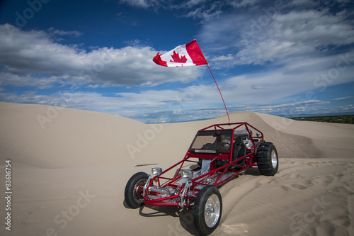 Shiny red sand dune buggy parked in the sand