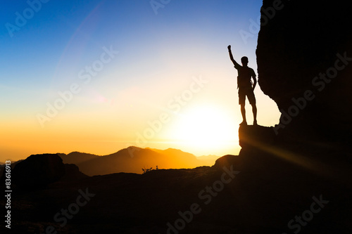 Man hiking climbing silhouette success in mountains sunset