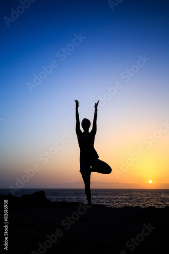 Woman exercising yoga sunset silhouette