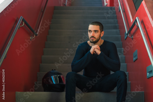 Handsome sexy and casual young man with helmet sitting on stairs
