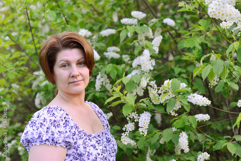 adult woman near blossoming bird cherry in the park adult woman near blossoming bird cherry in the park