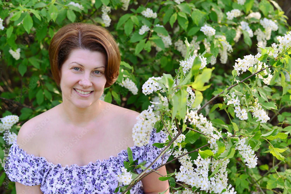 adult woman near blossoming bird cherry in the park adult woman near blossoming bird cherry in the park