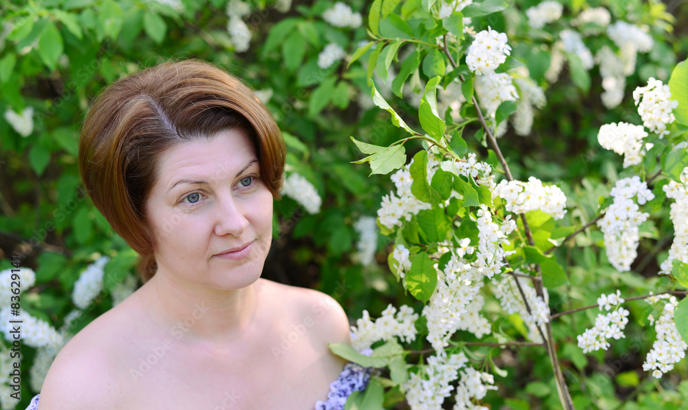adult woman near blossoming bird cherry in the park adult woman near blossoming bird cherry in the park