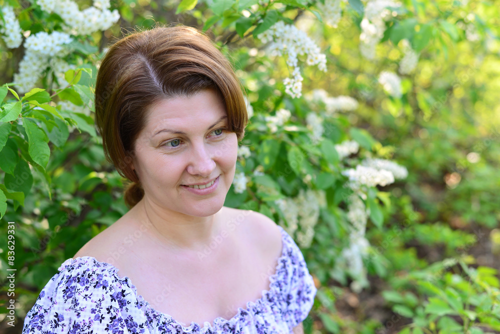 adult woman near blossoming bird cherry in the park adult woman near blossoming bird cherry in the park