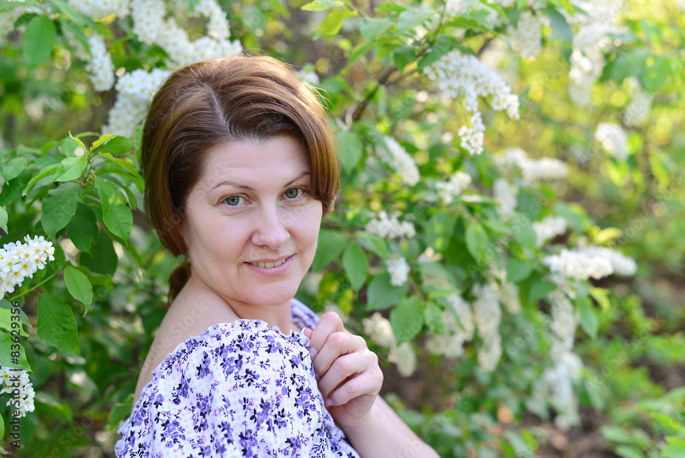 adult woman near blossoming bird cherry in the park adult woman near blossoming bird cherry in the park