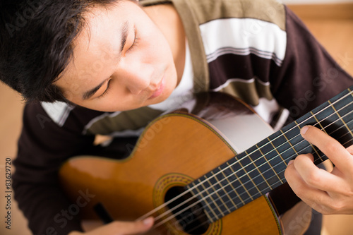 Practicing in playing guitar. Handsome young men playing guitar