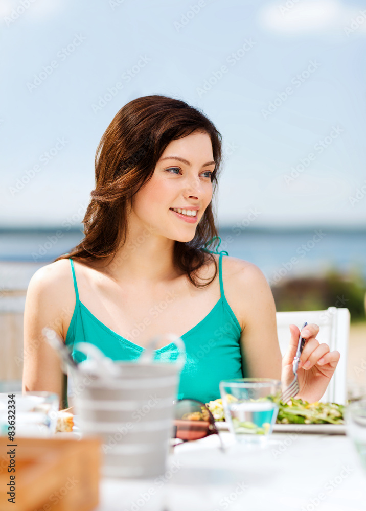 girl eating in cafe on the beach