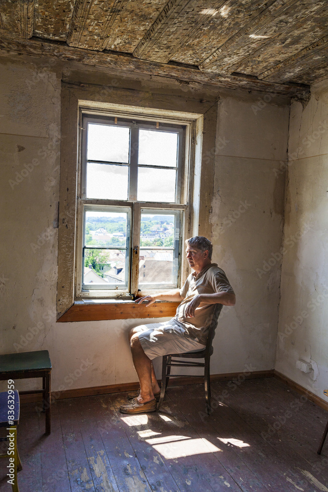man sitting at the window of an old house man sitting at the window of an old house