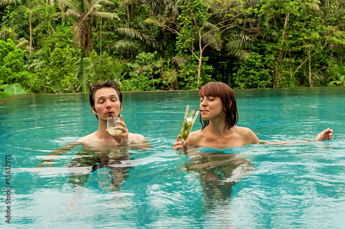 Man and woman with cocktails in the swimming pool 