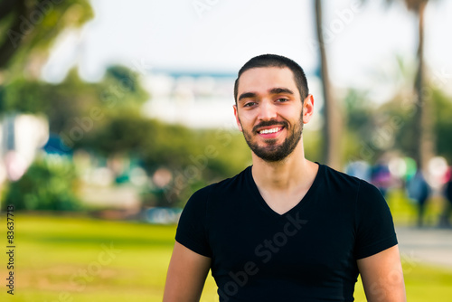 Handsome happy and casual young man standing in park © Mockup Cake