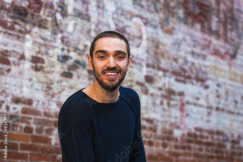 Handsome smiling and casual young man sitting on bench