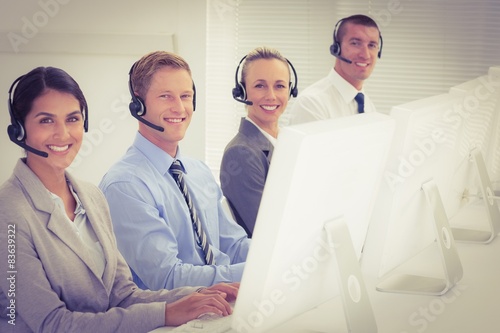 Business team working on computers and wearing headsets