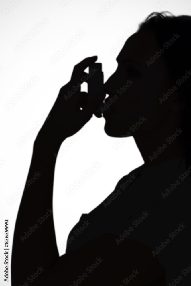 Composite image of asthmatic brunette using her inhaler 