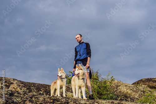 young caucasian male hiking with huskies in mountains © kurapatka