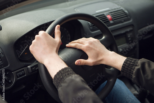 Close-up of male hand on steering wheel in car