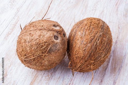 Two coconuts on white wooden table