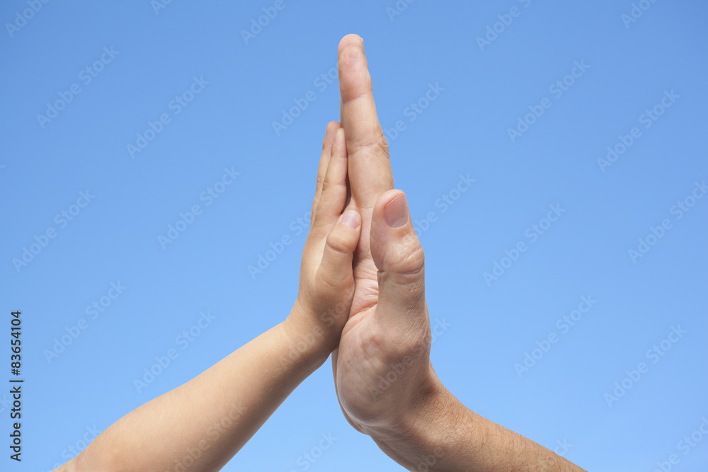 Father and son in high five gesture on a blue sky background Father and son in high five gesture on a blue sky background