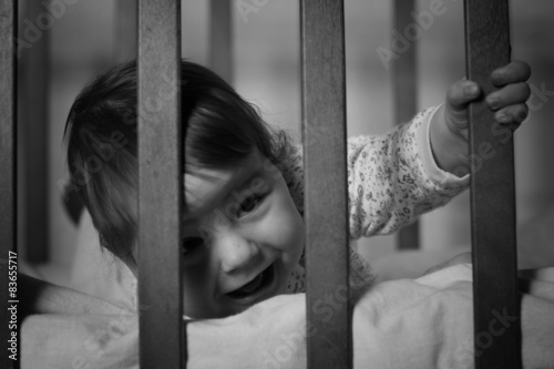 child playing in the bed behind bars