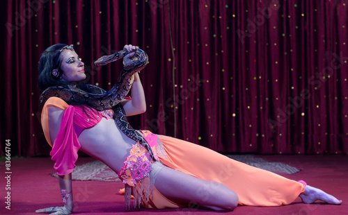 Фотография Female Snake Dancer Lying on Stage with Snake