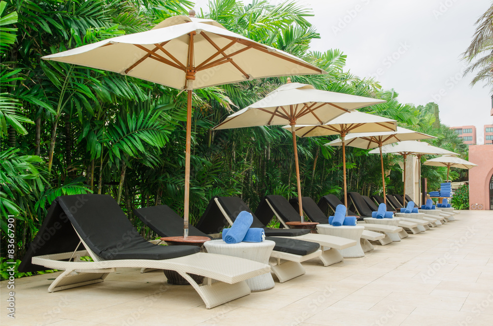 Many chairs and white umbrellas besides swimming pool