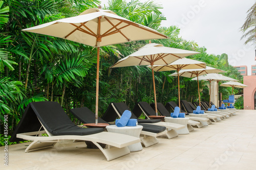 Many chairs and white umbrellas besides swimming pool © just2shutter