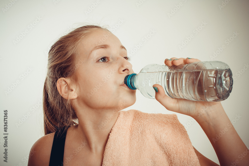 Teen girl drinks bottled water after exercising Teen girl drinks bottled water after exercising