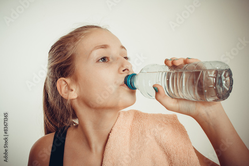 Teen girl drinks bottled water after exercising