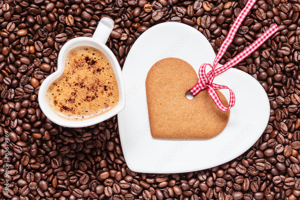 Heart shaped cup and cookie on coffee beans background Heart shaped cup and cookie on coffee beans background