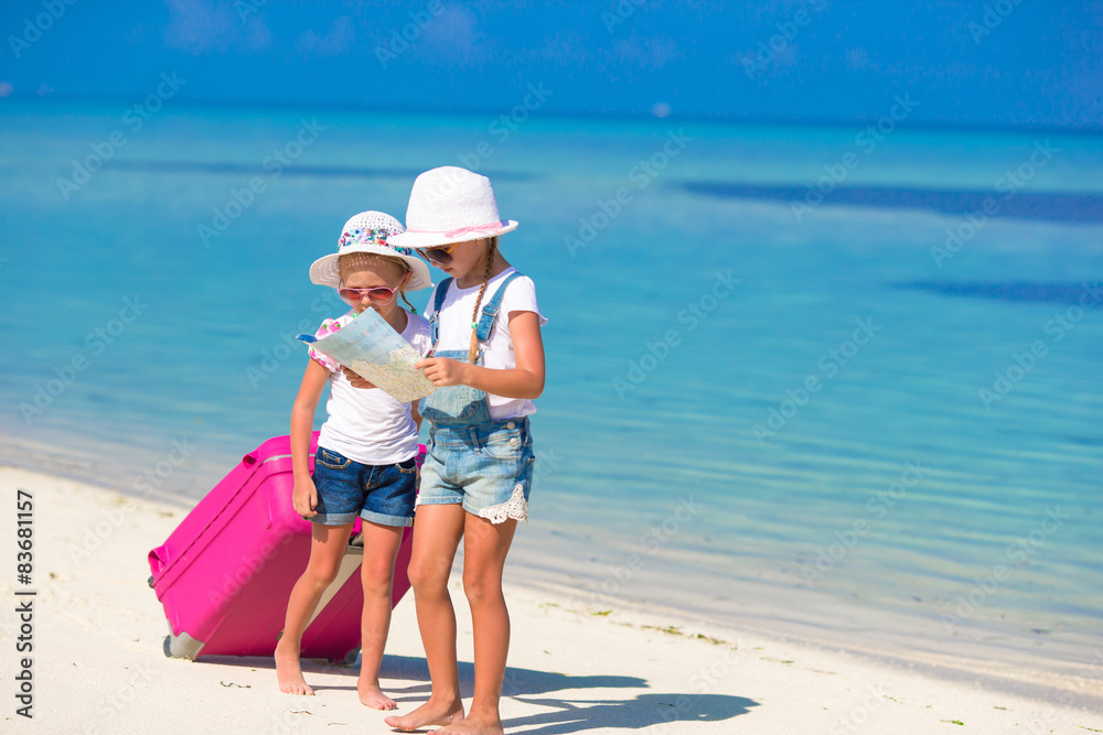 Little girls with big suitcase and map at tropical beach Little girls with big suitcase and map at tropical beach