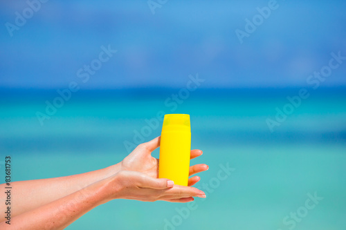 Female hands with suncream bottle background blue sea