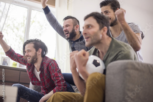 Group of friends watching football in living room
