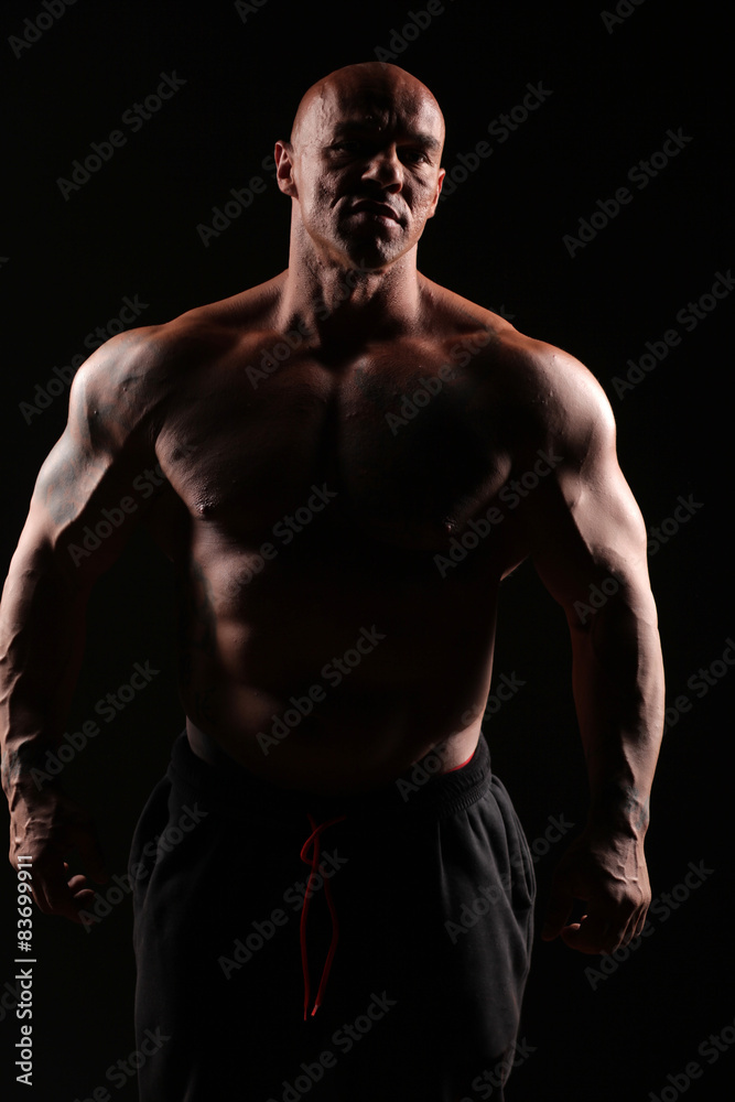 muscular bald man posing on a black background