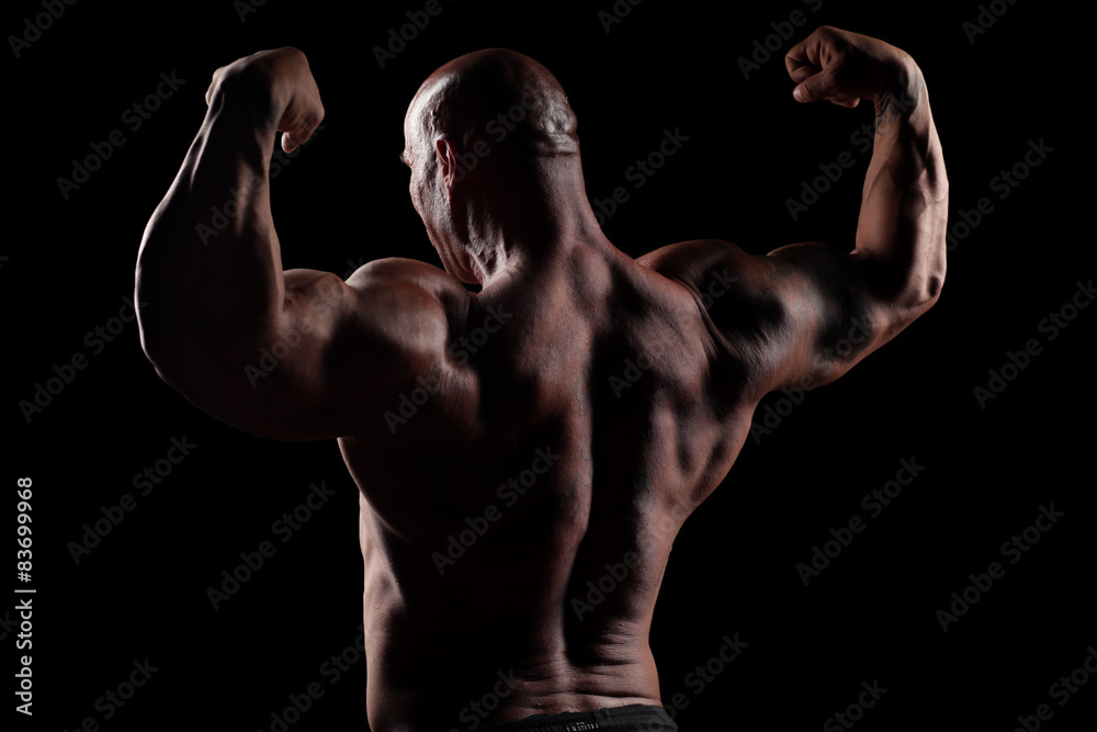back view on muscular bald man posing on a black background