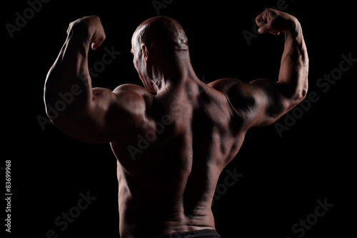 back view on muscular bald man posing on a black background