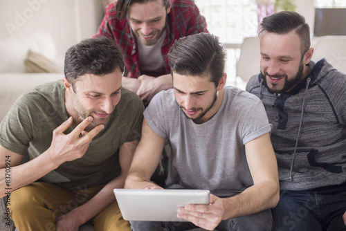 Group of men using digital tablet in living room